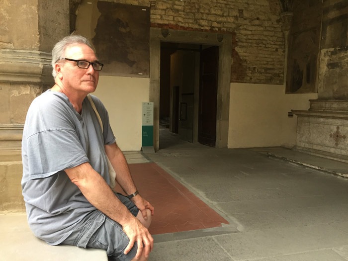 Ed Smith sits on a bench inside an old building, surrounded by historic architecture and soft lighting.